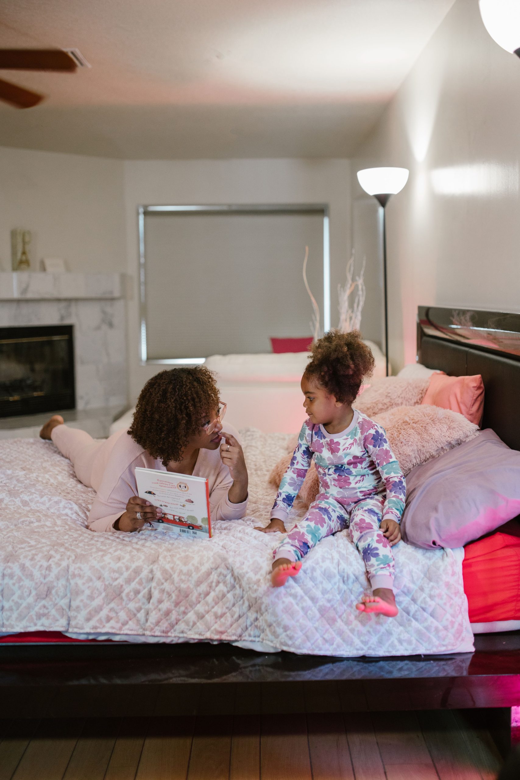 Black mother and daughter comparing children's bedtime pyjamas in a cozy bedroom
